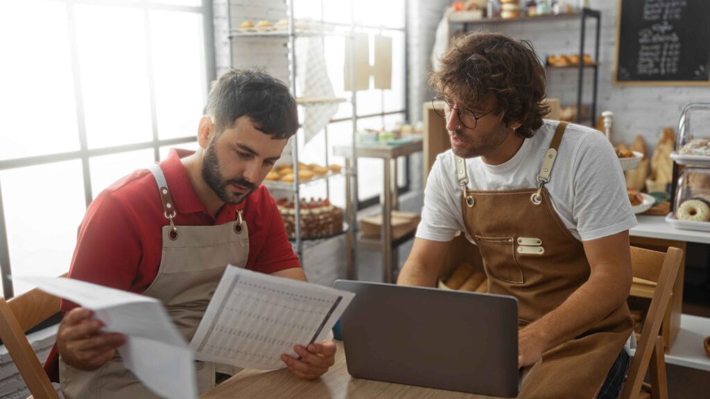 Profissionais em cozinha conferindo planilha de receitas e insumos para controle de rendimento